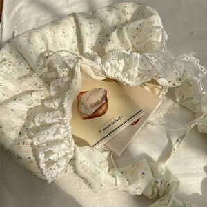 Détail d'un sac à main en dentelle florale avec nœuds sur tissu blanc plissé doux