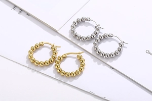 Detail shot of minimalist gold and silver bead hoop earrings on a clean background