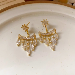 Macro detail of gold star earrings with marquise zircon fringe on ceramic tray