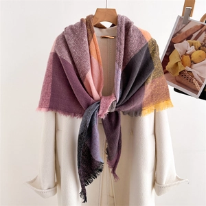 Close-up of pastel plaid cashmere scarf with soft fringes on a white winter coat