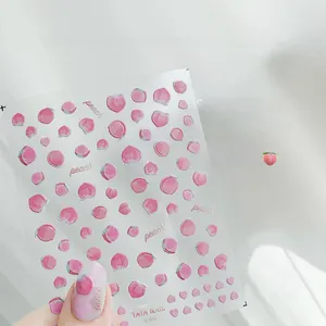 Dettaglio di adesivi 3D a rilievo per unghie con motivi di pesche e scritte