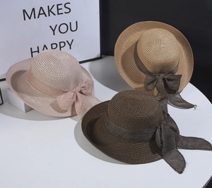 Detail of woven straw sun hats in beige and pink with elegant gauze ribbon bows