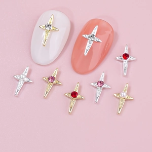 Macro detail of cross nail charms with rhinestones and pearls on pink background
