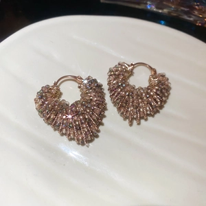 Macro detail of champagne crystal beaded heart earrings with rose gold huggie clasp