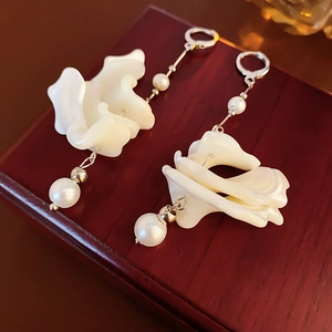 Dettaglio di orecchini a petalo con perle e nappe argentate su scatola di legno
