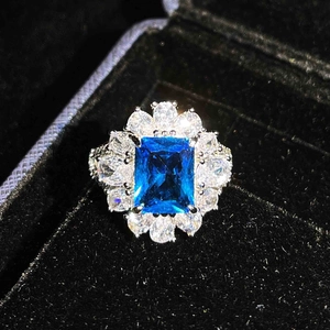 Macro view of a radiant emerald cut blue gemstone ring with a white crystal halo