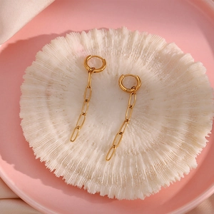 Detail of 18K gold-plated stainless steel paperclip chain earrings on white coral deco