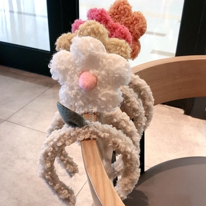 Cute plush flower headbands in multiple colors on a wooden chair with soft lighting
