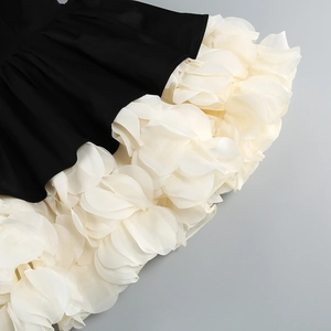 Close-up of layered 3D floral petals and monochrome contrast on a formal party dress