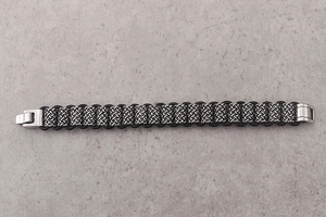 Detail of silver woven stainless steel bracelet with black leather edge and metal clasp