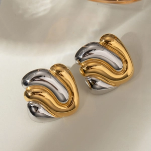Close-up of wavy gold and silver two-tone stainless steel geometric stud earrings