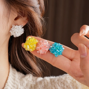 Close-up of beaded flower cluster earrings in white, yellow, pink, and blue colors