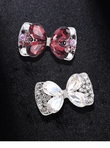 Detail of crystal bow brooches in red and iridescent silver on black background