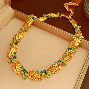 Detail of vintage gold leaf necklace with inlaid green and blue crystals in a gift box