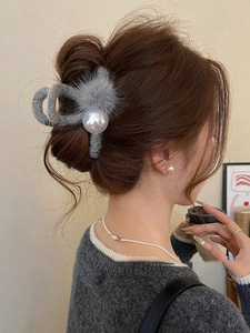 Detailed view of gray velvet hair claw clip with large pearl and soft pom-poms for winter