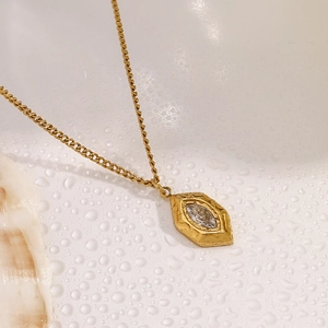 Detail of 18K gold rhombic necklace with clear crystal on wet surface and seashell