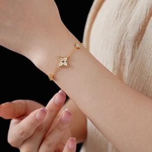 Detail of clover bracelet with gold plating and white zircon stones on model's wrist