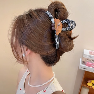 Détail d'une pince à cheveux à carreaux avec un décor de croissant porté par une femme
