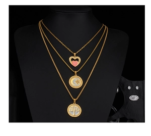 Detailed view of triple-layered gold necklace with heart, moon and tree of life pendants