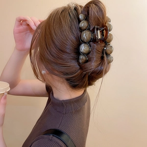 Brown amber geometric hair claw clip with resin spheres shown on a model's hairstyle