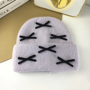Detailed close-up of lavender knit beanie with delicate black velvet bow embellishments