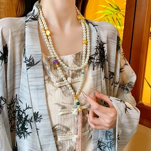 Detailed view of double-layer pearl necklace featuring pink tassels and colorful beads