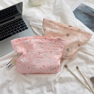 Quilted cotton cosmetic bags with cartoon bunny patterns in pink and beige on white linen