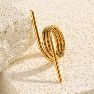 Nahaufnahme eines 18K vergoldeten Spiralrings auf weißem Travertin-Stein