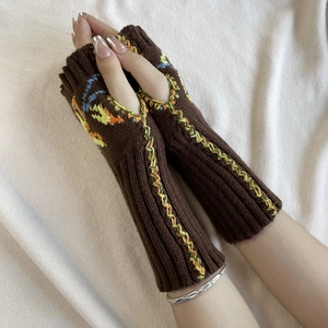 Detailed close-up of brown knit fingerless gloves with colorful floral embroidery