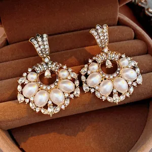 Vintage gold pearl drop earrings with crystal clusters on a velvet jewelry display box