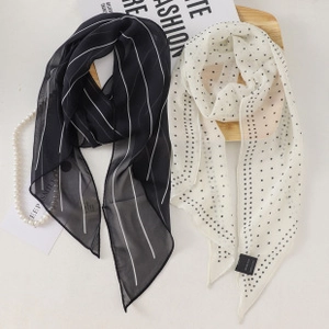 Detail of elegant black and white striped and polka dot chiffon scarves with pearls