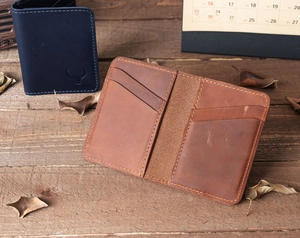 Detail of slim genuine leather card holders in brown and navy blue on wood
