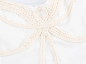 Dettaglio della decorazione a nodi intrecciati su un abito bianco stile bohémien