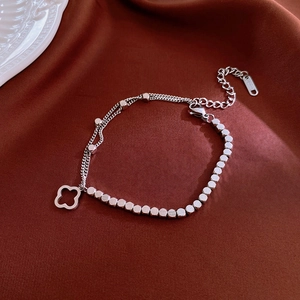 Detail of silver clover pendant and square metal beads on a stainless steel bracelet