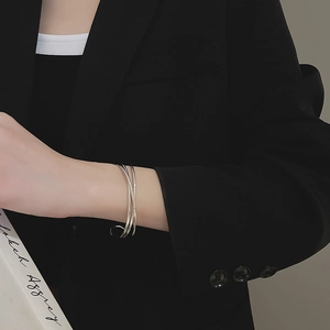 Close-up of polished silver multi-layer wave cuff bracelet on model wearing black suit