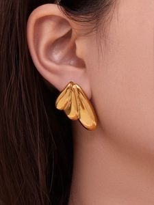 Detailed view of fan-shaped golden earrings with polished leaf-like layers on a model