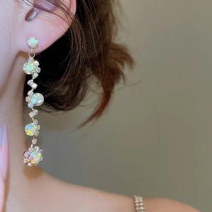 Close-up of golden tassel earrings with multi-color rhinestones on a model
