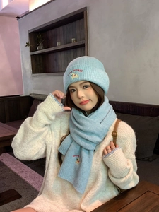 Close-up of light blue knit hat and scarf set with lucky puppy embroidery detail