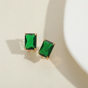 Macro view of emerald green square cut gemstone earrings in gold-tone claw setting