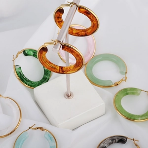 Chic resin hoop earrings in assorted marble colors with gold hardware on a display stand
