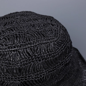 Detailed macro view of black hollow-out hand-woven straw fisherman hat texture