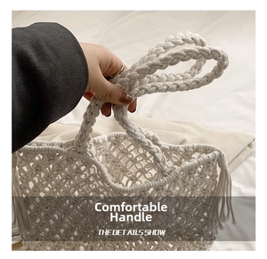Detail of white handmade woven cotton bag with tassel elements and bohemian braided handle