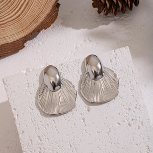 Macro detail of geometric leaf earrings with silver finish and radial stripes texture