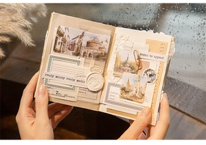 Detail of vintage DIY travel scenery scrapbook stickers held in hands by a warm window