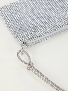 Detailed close-up of sparkling silver rhinestone mesh and metallic zipper on evening bag