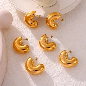 Set of three pairs of chunky gold C-shaped hoop earrings on a ceramic dish
