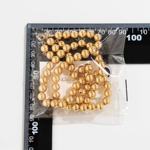 Detailansicht einer goldfarbenen Perlenkette mit Metallglanz auf einer Messskala