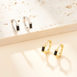 Macro shot of S925 silver hoop earrings with rectangular black zircon and gold plating