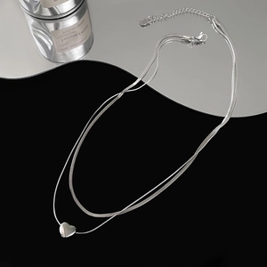 Double-layered silver heart necklace with a sleek snake chain on a black background