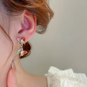 Close-up of model wearing colorful butterfly drop earrings with cubic zirconia